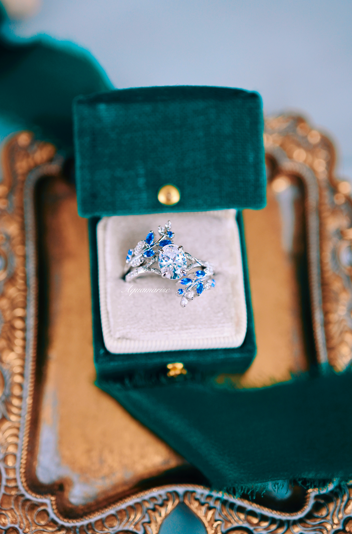 Blue Sapphire & Simulated Diamond Leaf Engagement Ring Set in Sterling Silver displayed in a green velvet box on an ornate gold tray by Aquamarise.