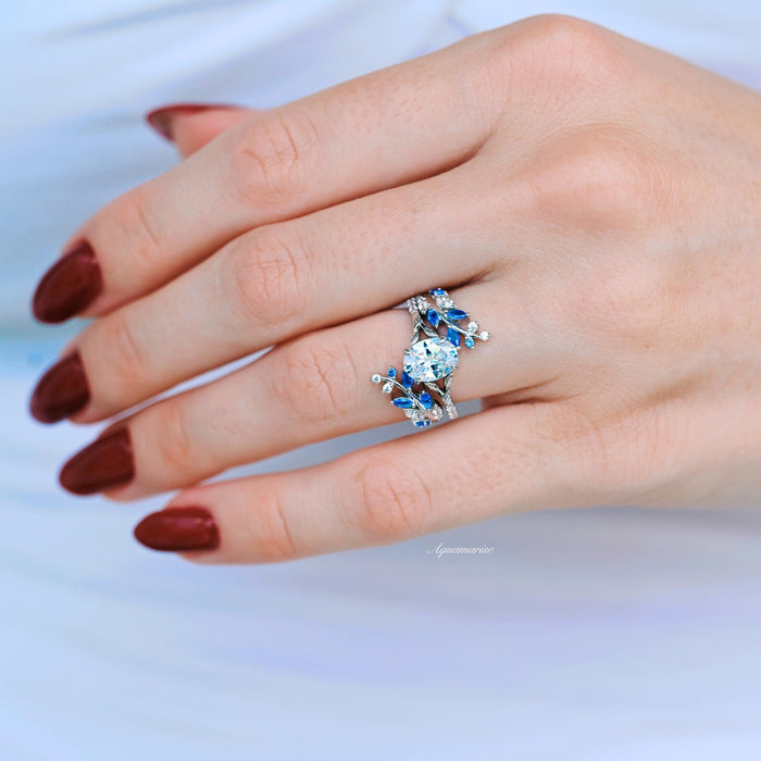 Blue Sapphire & Moissanite Leaf Ring Guard in 14K White Gold by Aquamarise Gold featuring vine-inspired design with lab-grown blue sapphires and sparkling moissanite on a hand model.