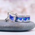 Borealis & Tanzanite Couples Ring Set- Northern Lights & Trees featuring a radiant tanzanite gemstone with diamond accents alongside a polished band showcasing a vibrant blue and green aurora borealis inlay with engraved tree silhouettes by Aquamarise.