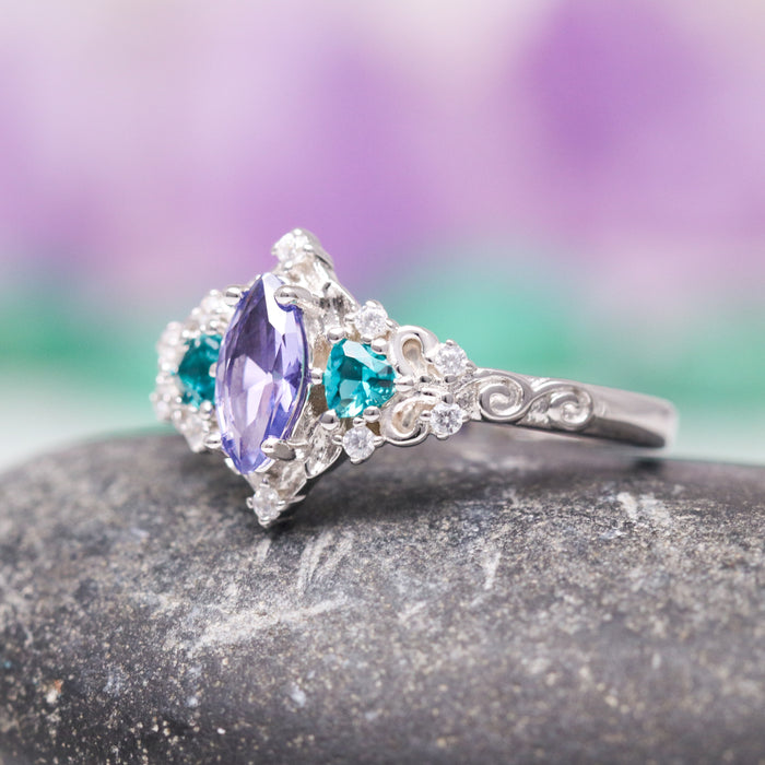 Borealis Tanzanite & Teal Sapphire Couples Ring Set (Mountain Range) by Aquamarise, featuring a marquise-cut tanzanite center stone flanked by teal sapphire accents and delicate diamond clusters on an intricately detailed silver band, from Matching Couples' Rings and September and December Birthstone Jewelry collections.