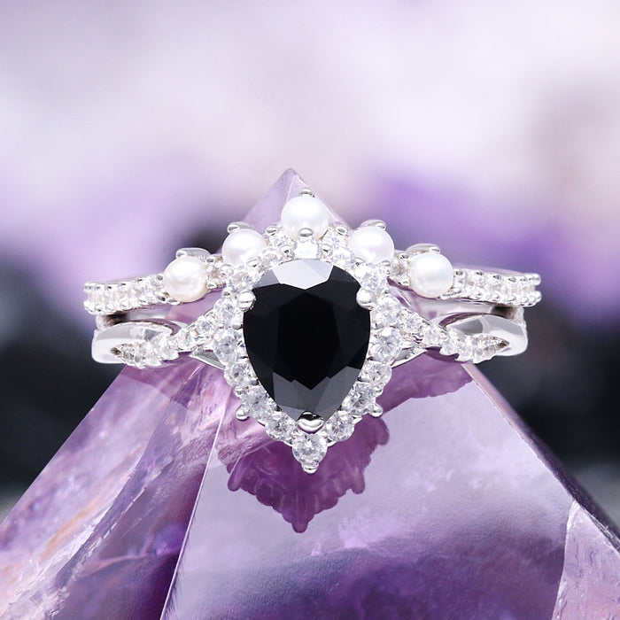 Briar Black Onyx & Pearl Ring Set in Sterling Silver by Aquamarise showcases a pear-shaped black onyx center stone surrounded by delicate pearls and sparkling accents, perfect for lovers of unique, non-traditional engagement rings.