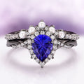 Ring with blue heart-shaped gemstone and pearls on a gradient background