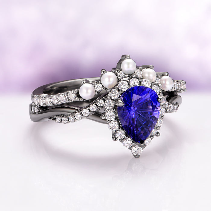 Briar Blue Sapphire and Pearl Engagement Ring Set in Black Ruthenium by Aquamarise features a pear-shaped blue sapphire centerpiece surrounded by freshwater pearls and sparkling simulated diamonds on a black ruthenium plated sterling silver band, part of June and September Birthstone Jewelry and Lovers of the Dark™ collections.