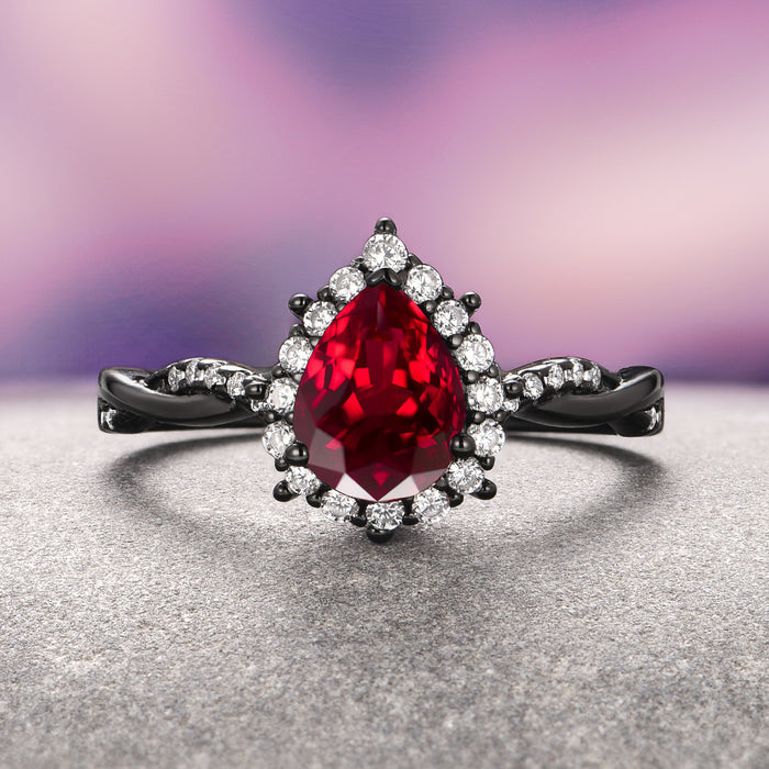 Briar Natural Red Garnet Couples Ring Set by Aquamarise featuring a pear-shaped red garnet center with diamond halo on black finish band, matching couples rings, elegant gemstone jewelry.