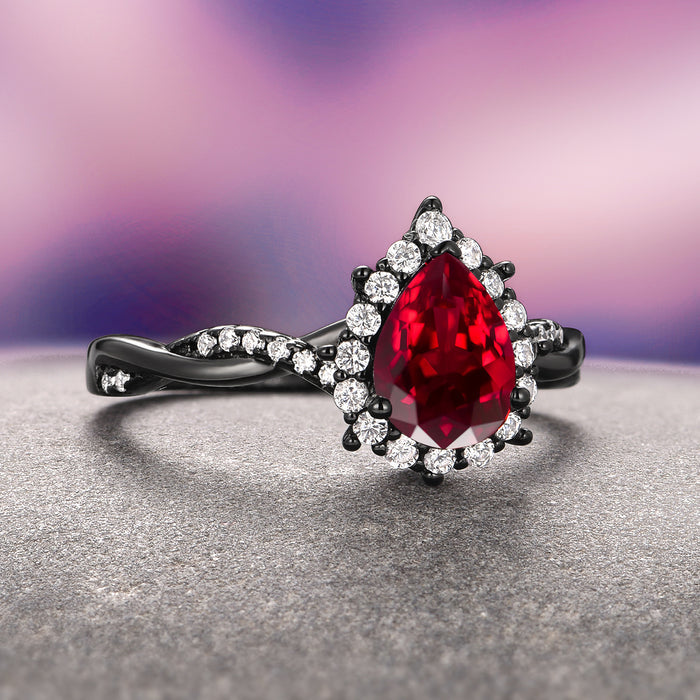 Briar Natural Red Garnet Couples Ring Set showcasing a pear-shaped red garnet surrounded by diamonds on a black twisted band by Aquamarise, symbolizing matching couples rings.