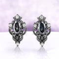 Carmilla gray moissanite stud earrings in black ruthenium, oval centers with black onyx pears and carved leaf and scroll frames