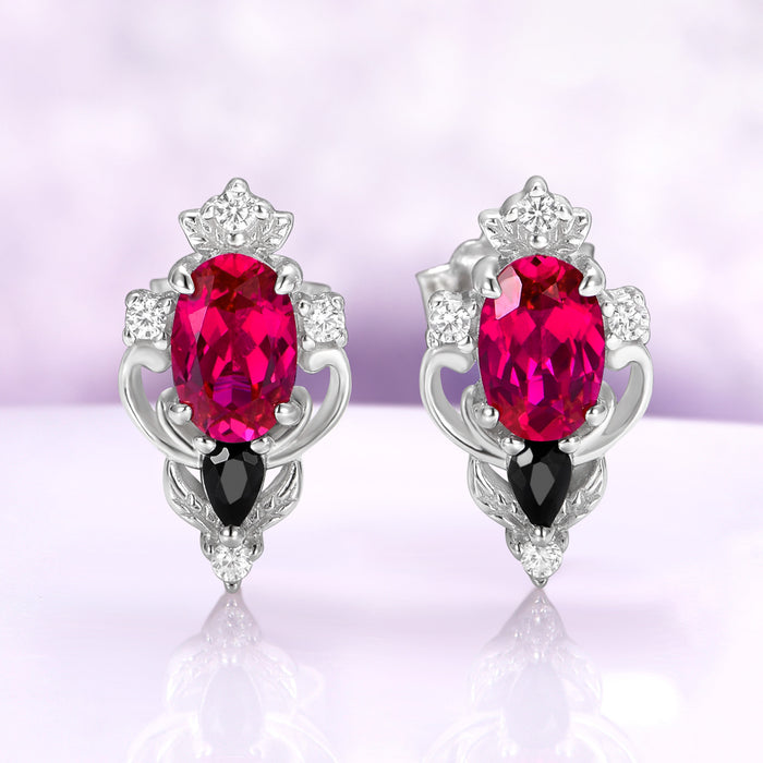 Carmilla lab-grown ruby stud earrings in sterling silver, oval centers with black onyx pears and carved leaf and scroll frames