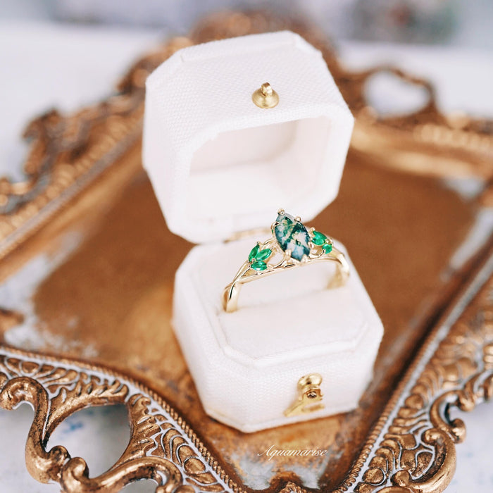 Celtic Knot Moss Agate & Gold Leaf Couples Ring Set in a white velvet box displayed on ornate gold tray, featuring green moss agate and gold leaf design by Aquamarise.