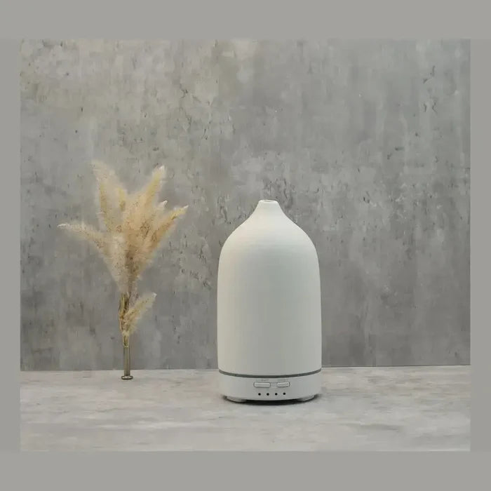 color-changing ceramic essential oil diffuser on a modern stone background with decorative plant.