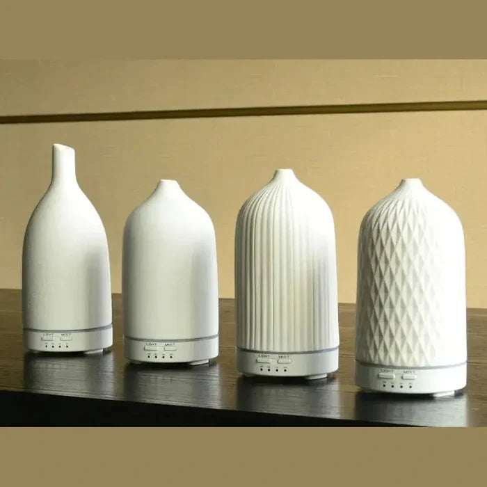 Four color-changing ceramic essential oil diffusers on display, showcasing unique designs for home ambiance.