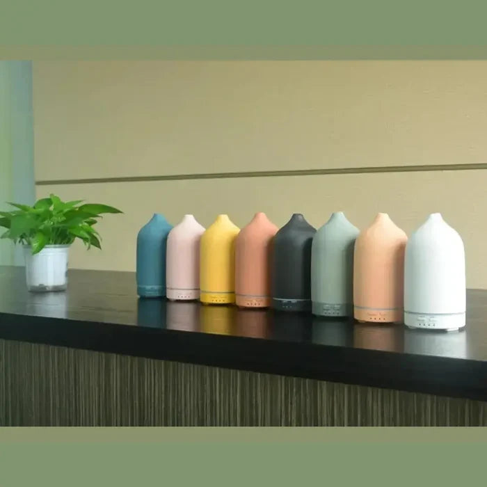 color-changing ceramic essential oil diffuser in various colors on a table beside a plant