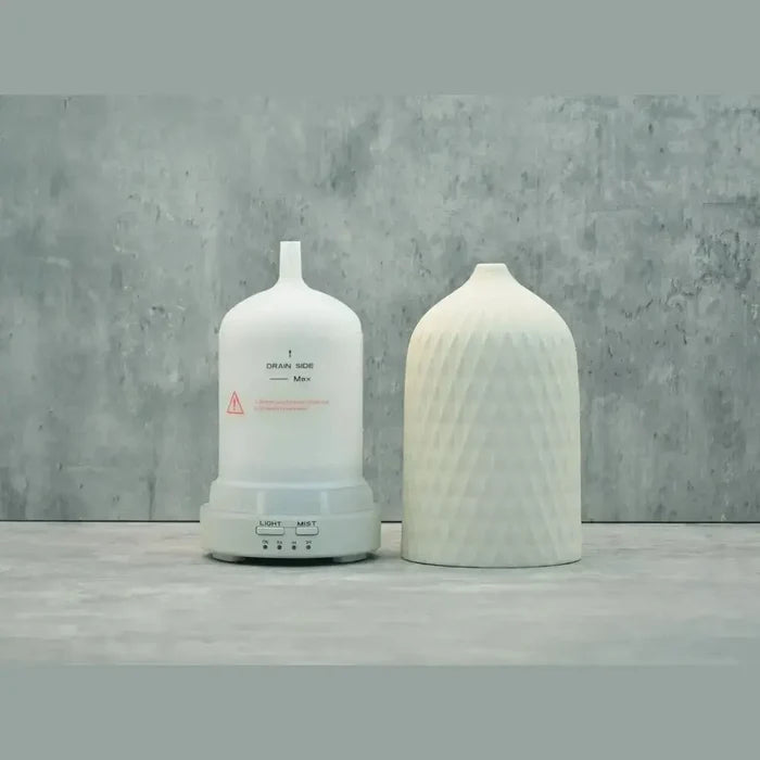 color-changing ceramic essential oil diffuser displayed beside a modern humidifier on a textured surface.