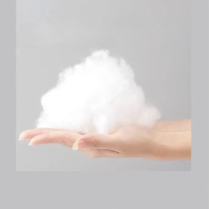 Soft white material held in a hand, showcasing plush filling suitable for cervical massage pillow.
