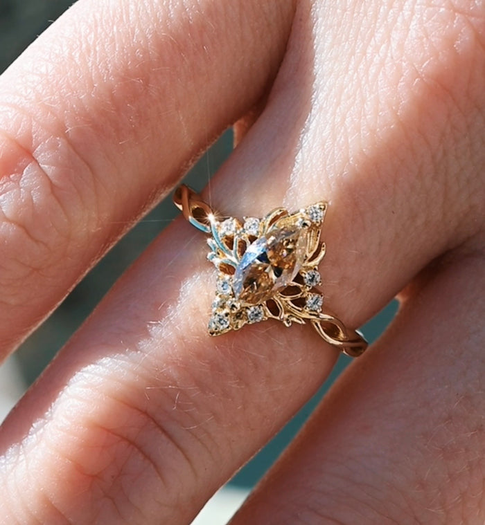 Gold ring with diamond accents on a finger against a blurred background