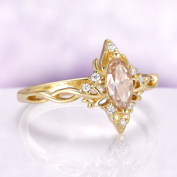 Gold ring with a pink gemstone and diamond accents on a light purple background
