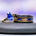 Coffin Cut Blue Sapphire and Gold Leaf Couples Ring Set featuring a faceted black band with blue sapphire and gold leaf inlay and a gold ring with geometric blue sapphire by Aquamarise.