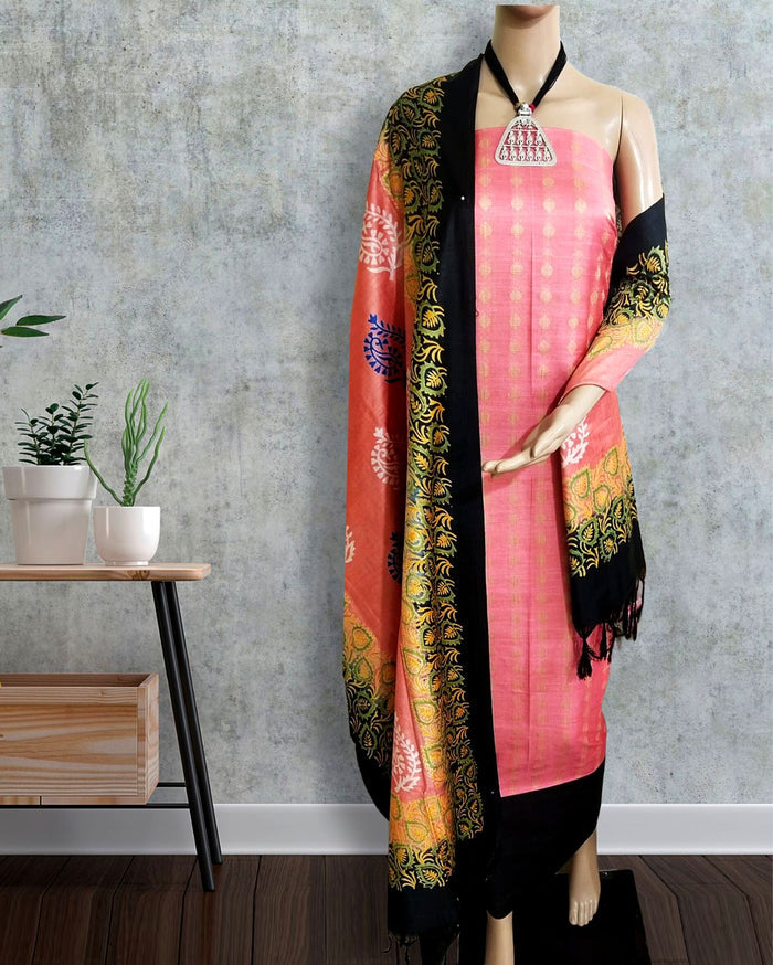 Unstitched Katan silk suit set with a soft coral pink fabric printed in small metallic dash motifs and a contrasting black piece with dense floral vine block print and a wide ornate multi-layered fringed border.