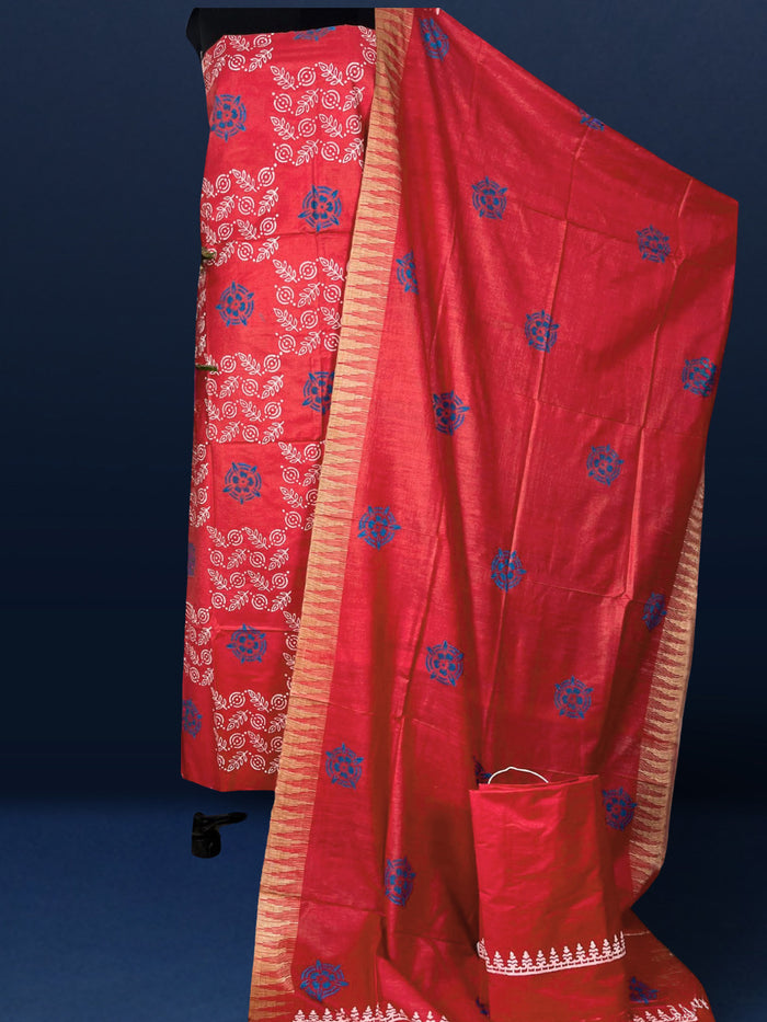 Coral red Katan silk suit set hand block printed with blue circular motifs and small white leaf sprigs with metallic gold detail, and a frayed fringe on the dupatta.
