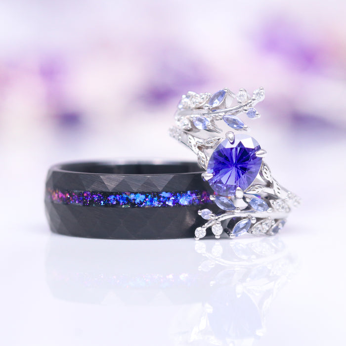 Orion Nebula™ Hammered Wedding Band in Black Tungsten (8mm) by Aquamarise paired with a silver ring featuring a vibrant purple gemstone and intricate leaf details, showcasing distinctive men's and women's jewelry designs.