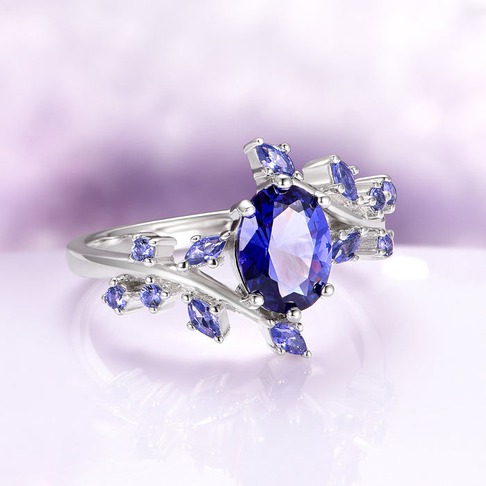Orion Nebula™ & Cornflower Sapphire Leaf Couples Ring Set by Aquamarise, featuring a silver band with a large oval sapphire surrounded by smaller cornflower sapphires in a leaf-inspired design.