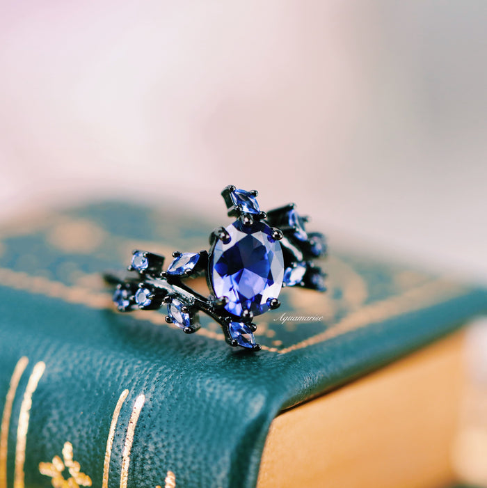 Cornflower Sapphire & Orion Nebula™ Couples Ring Set by Aquamarise showcasing a vibrant cornflower sapphire surrounded by cosmos-inspired blue gems on a black band for a unique celestial design.