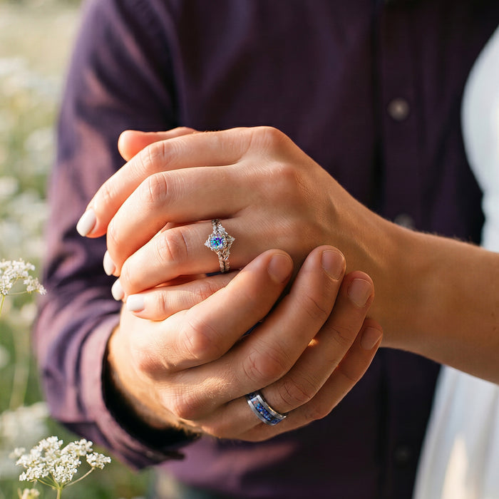Crushed Rainbow Inlay Tungsten Wedding Band in Tungsten Carbide (8mm) worn on groom’s hand, paired with a delicate engagement ring, showcasing Aquamarise’s unique couple rings collection.