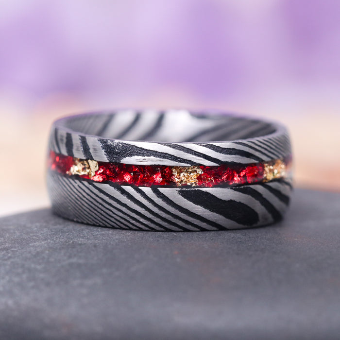 Crushed Red Garnet and Gold Leaf Wedding Band- 8MM Damascus Steel by Aquamarise, featuring a textured black and silver Damascus steel band with a vivid inlay of crushed red garnet and gold leaf, part of Men's Wedding Bands and January Birthstone Jewelry collections.