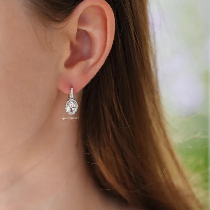 Simulated Diamond Dangle Earrings in Sterling Silver by Aquamarise, featuring sparkling oval-cut stones with delicate accents, styled on an ear in natural light.