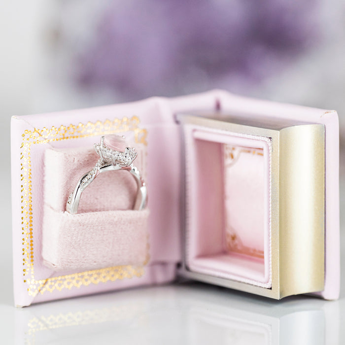 Dawn Court Leather Book Ring Box - Blushing Dawn Edition (Small) by Aquamarise holding a delicate silver engagement ring in a soft pink velvet case from the Ring Boxes & Keepsake Proposals collection