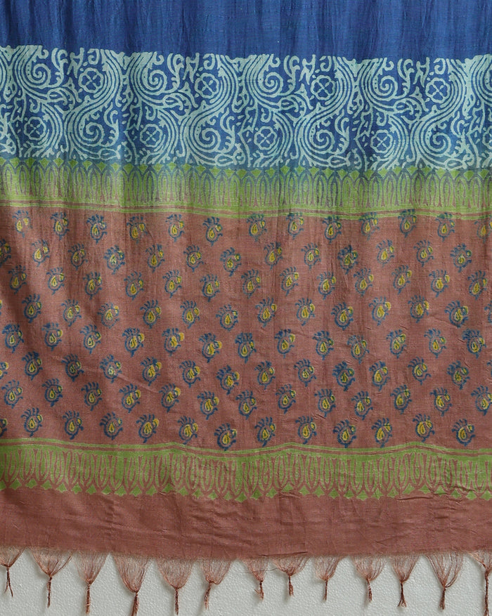 Deep blue katan silk unstitched suit with all-over block-printed floral and diamond motifs, a rust-orange dupatta with wide geometric end borders, and a plain blue bottom.