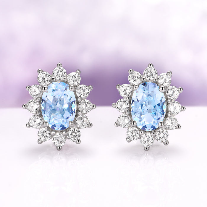 Diana Halo Oval Aquamarine Stud Earrings in Sterling Silver by Aquamarise, featuring oval aquamarine centers surrounded by sparkling simulated diamonds in a delicate halo setting.