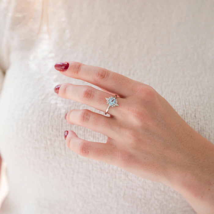 Hand wearing a ring with a blue gemstone on a white background
