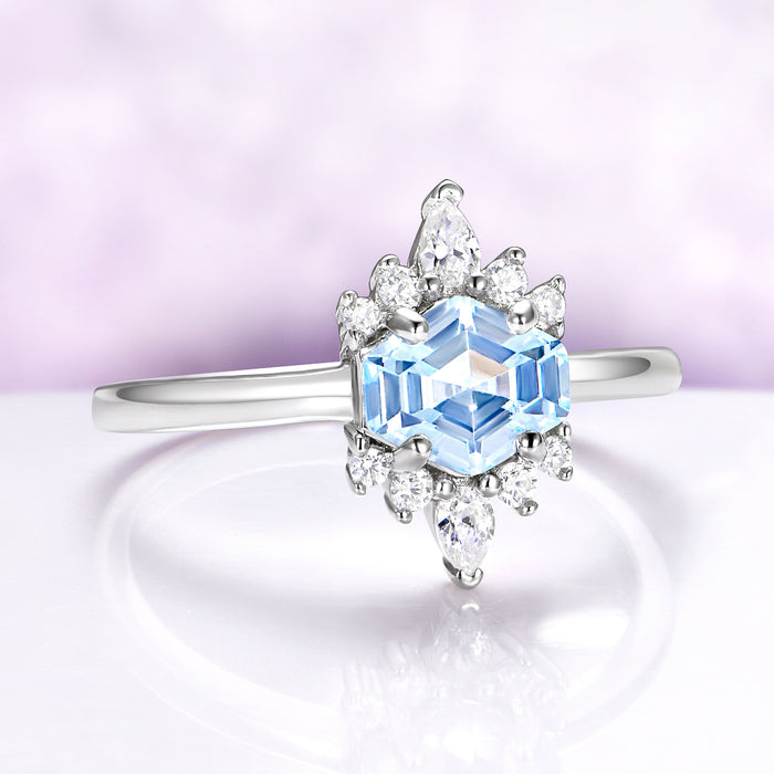 Elegant ring with a blue gemstone and diamond accents on a soft purple background