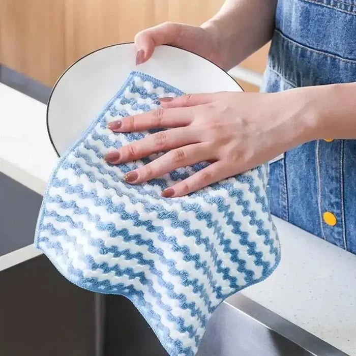 Person using an eco-friendly microfiber dishcloth to dry a clean plate in the kitchen