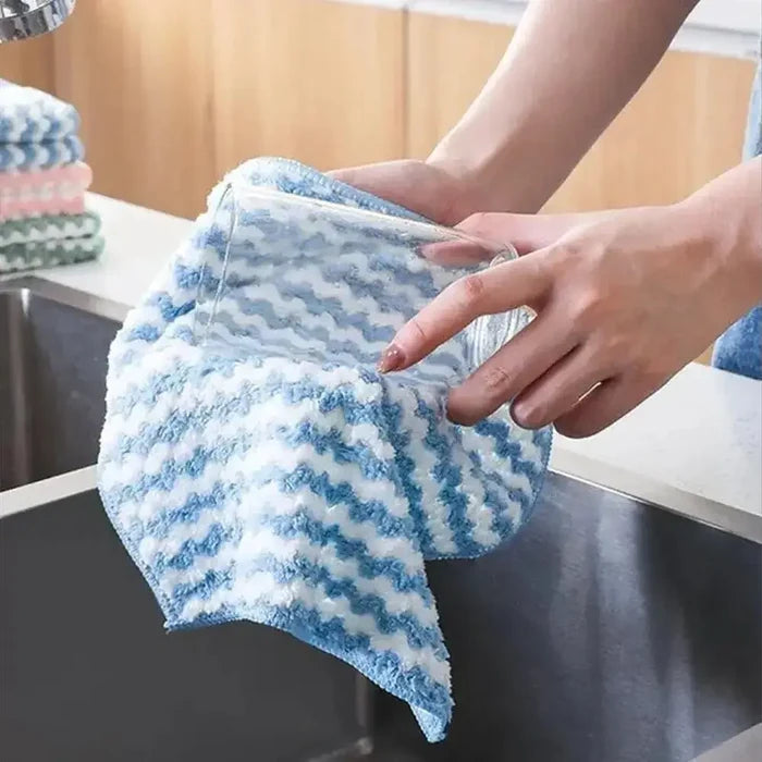 Person using an eco-friendly microfiber dishcloth to clean a glass in the kitchen sink.