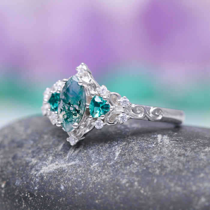 Elain Moss Agate & Teal Sapphire Leaf Ring- 14K White Gold featuring a marquise-cut moss agate with teal sapphire accents set in a white gold band adorned with intricate vine and leaf details by Aquamarise Gold.