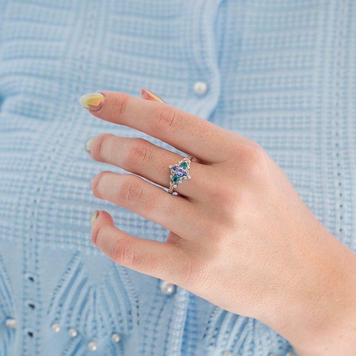 Borealis Tanzanite & Teal Sapphire Couples Ring Set (Mountain Range) by Aquamarise displayed on a hand, featuring a marquise-cut tanzanite with teal sapphire accents and diamond details, part of Matching Couples' Rings and September and December Birthstone Jewelry collections.