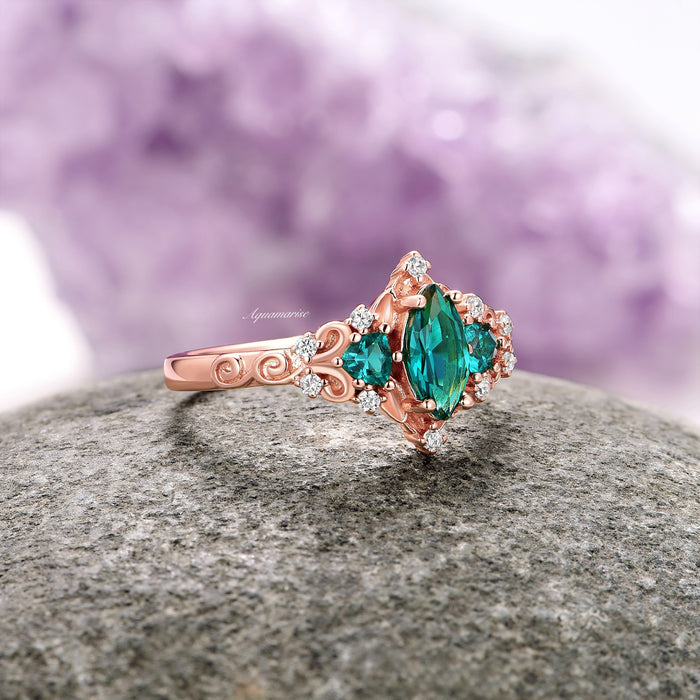 Elain Teal Sapphire Fairy Engagement Ring in 14K Rose Gold Vermeil with a marquise teal sapphire center, surrounded by sparkling stones, on a detailed rose gold vermeil band by Aquamarise.
