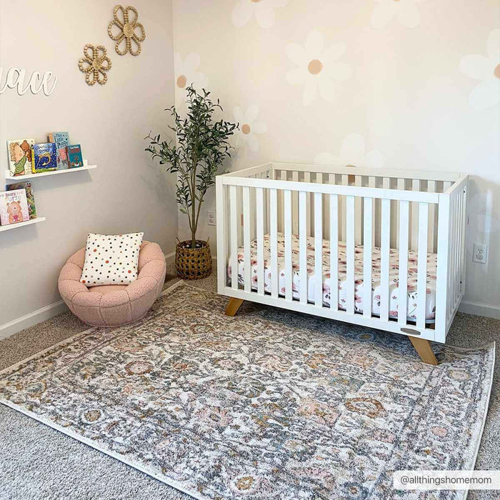 Herstmonceux elegant area rug in a nursery with crib, pink chair, and wall decor.