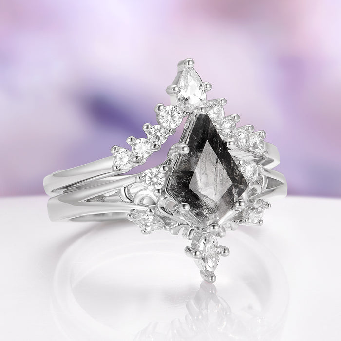 Silver ring with a central black diamond and smaller clear diamonds on a blurred purple background