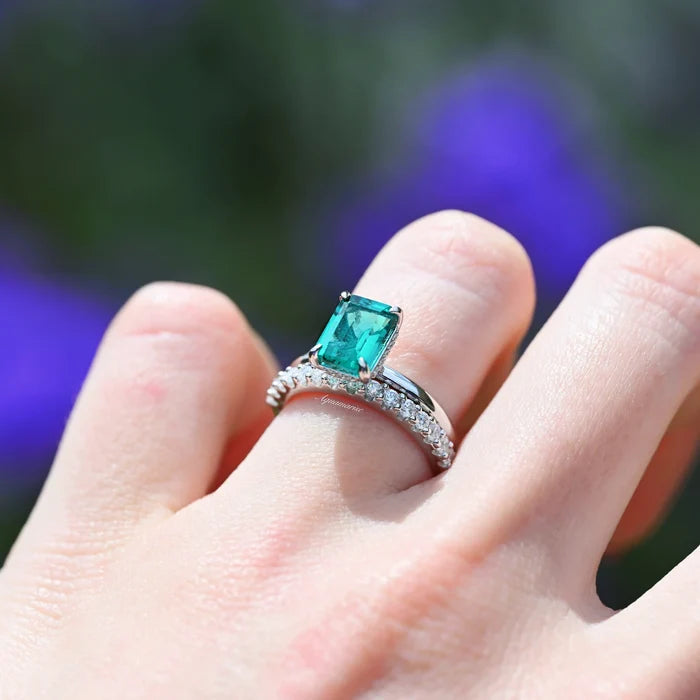 Emerald Engagement Ring in 14K White Gold (Hidden Halo) by Aquamarise Gold, featuring a deep green emerald-cut emerald and diamond-accented white gold band worn on a hand.