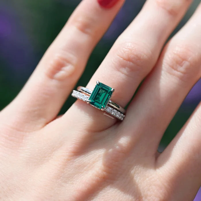 Emerald Engagement Ring in 14K White Gold (Hidden Halo) by Aquamarise Gold, featuring a deep green emerald-cut emerald paired with a diamond-accented white gold band on a hand.