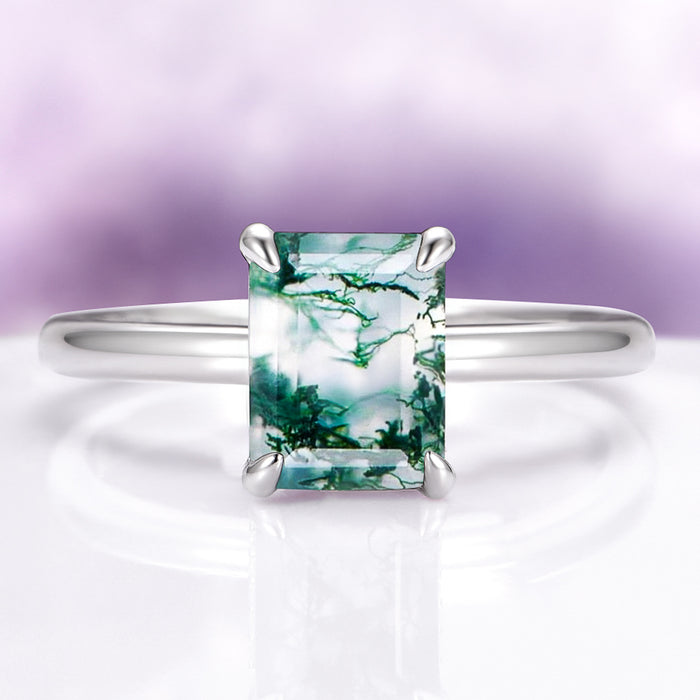 Moss Agate Engagement Ring in 14K White Gold (Hidden Halo) by Aquamarise Gold, showcasing an emerald-cut green moss agate on a sleek white gold band with a nature-inspired design.