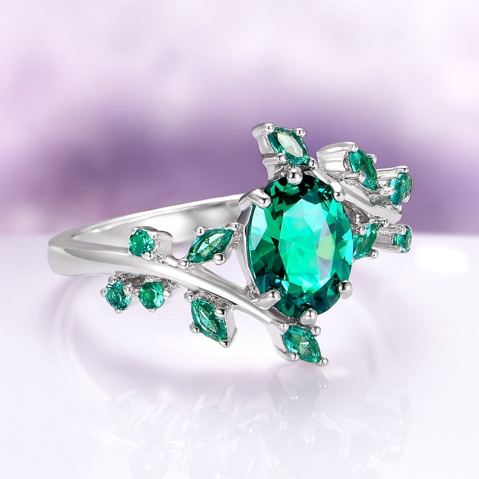 Oval Cut Lab-Grown Emerald Leaf Engagement Ring in 14K White Gold by Aquamarise Gold, featuring a vibrant oval emerald and delicate leaf-shaped accents in a nature-inspired, elegant design.