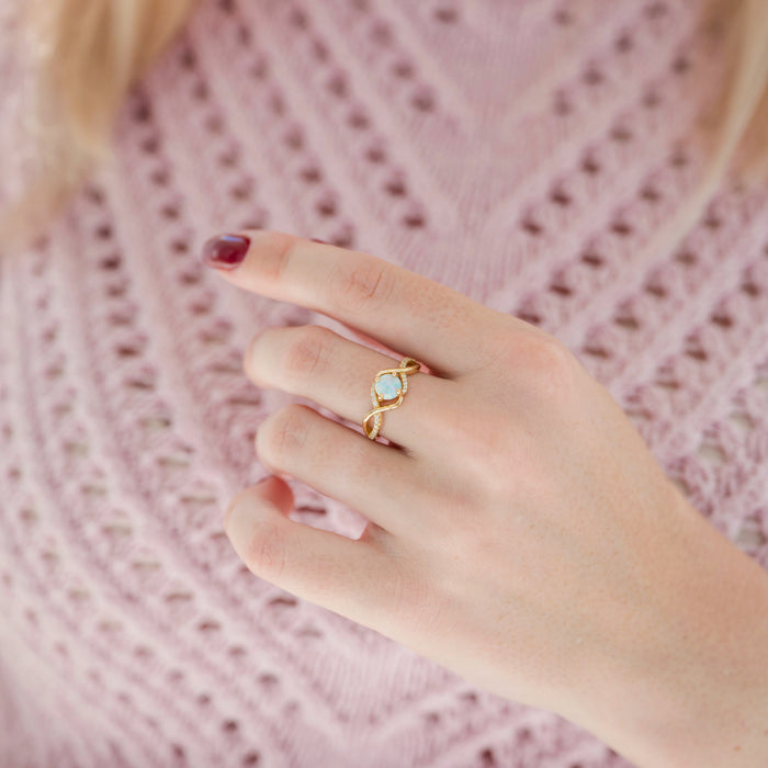 Entwined Natural Australian Opal Engagement Ring in 14K Solid Yellow Gold by Aquamarise Gold, featuring a radiant opal set in a twisted gold band, worn on a hand with soft pink sweater background.