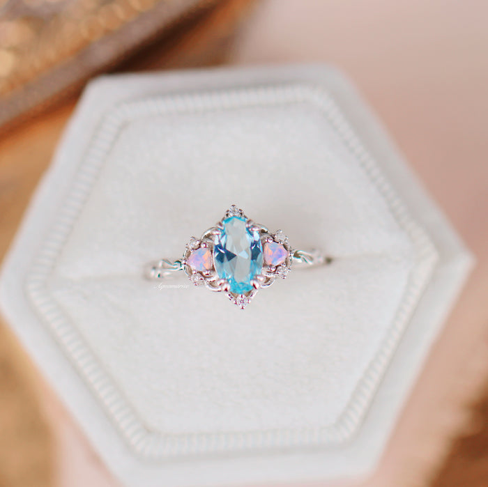Esme Aquamarine & Opalescent Sapphire Ring in 14K White Gold featuring an oval aquamarine center flanked by two opalescent sapphires on a delicate white gold band by Aquamarise Gold.