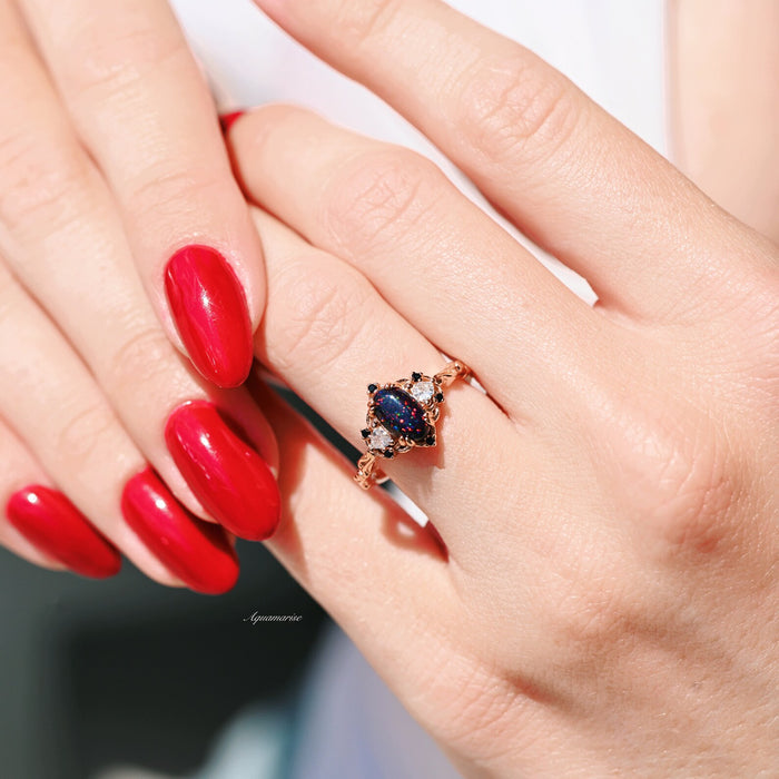 Esme Black Fire Opal Ring- 14K Rose Gold Vermeil by Aquamarise featuring an oval black fire opal with delicate rose gold band, styled on hand with glossy red nails.