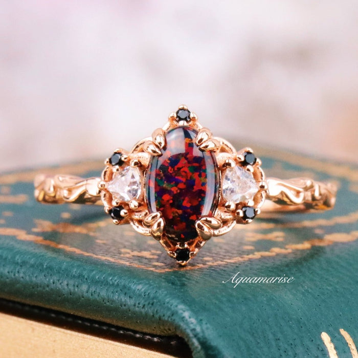 Esme Black Fire Opal Ring- 14K Rose Gold Vermeil featuring an oval black fire opal with red flashes, black and clear gemstone accents on an ornate rose gold band by Aquamarise.