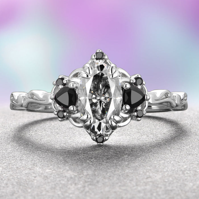 A 14K white gold ring with an oval-shaped gray moissanite center stone and black onyx accents on a plain background.