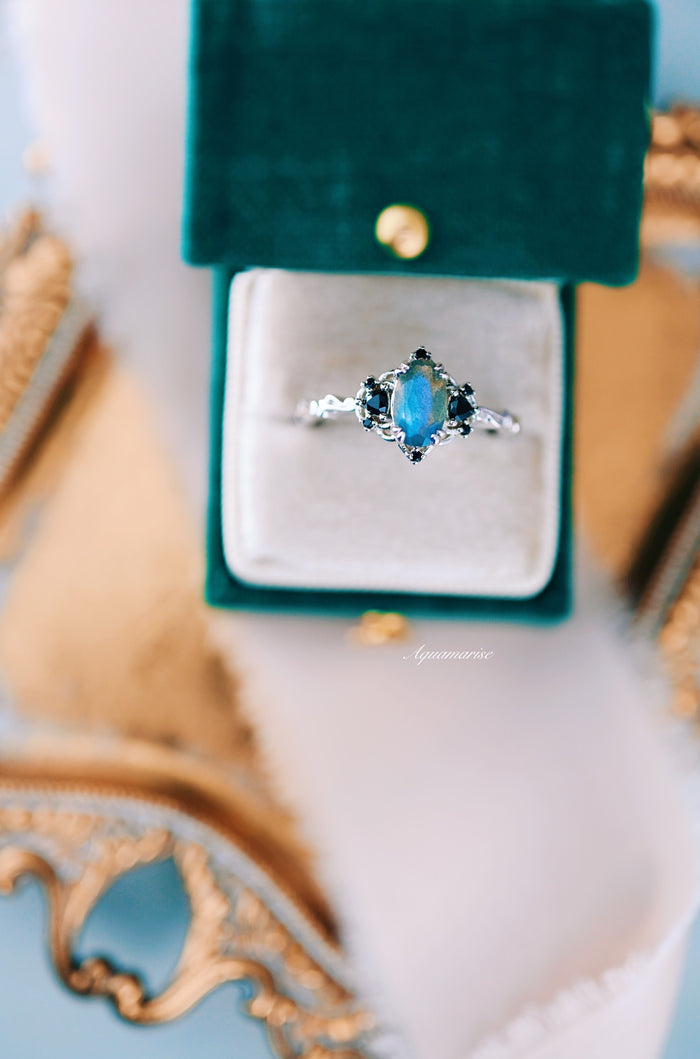 Esme Labradorite & Black Onyx Engagement Ring in 14K White Gold by Aquamarise Gold, featuring an iridescent marquise labradorite center stone with black onyx accents on a delicately detailed white gold band, showcased in a velvet ring box.